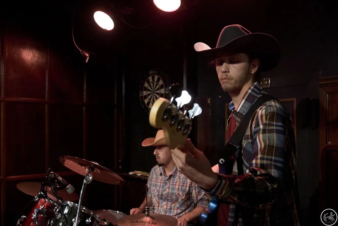 Alex Brisson à la basse en spectacle, batteur en chapeau de cowboy en arrière